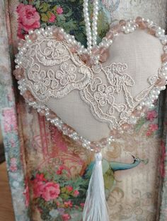 a heart with pearls and tassels hanging from it's sides on a wall