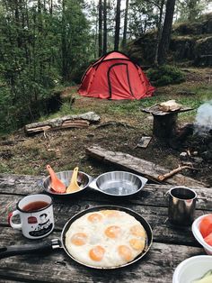 an outdoor table with food on it and a tent in the background