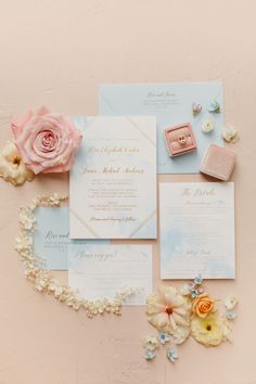 the wedding stationery is laid out with flowers and jewelry