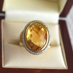 Vintage cocktail ring by jeweler David Yurman crafted in 18-karat yellow gold. It features a checkerboard-cut citrine weighing approximately 12.5 carats (18.0 x 13.0 x 8.0 mm), surrounded by a double halo of brilliant-cut diamonds totaling about 1 carat, with G/H color and VS clarity. The ring's band has a twisted design, and the signature "D.Y" for David Yurman is found on the inside. Weight: 17.9 g Size: 51 FR (5.75 US - L UK) Metal: 18-karat Yellow Gold Stones: citrine (approx. 12.5 carats) a Luxury Faceted Yellow Ring, Luxury Faceted Topaz Ring, Formal Yellow Gold Citrine Topaz Ring, Formal Yellow Topaz Ring, Formal Citrine Diamond-cut Ring, Formal Citrine Diamond Cut Ring, Formal Citrine Ring With Diamond Cut, Formal Yellow Gold Topaz Ring With Diamond Cut, Luxury Oval Faceted Topaz Ring