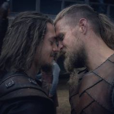 two men with long hair and beards standing next to each other