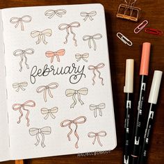 an open notebook with the word february written on it next to some markers and pens