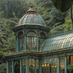 a green building with lots of windows in the middle of trees and bushes around it