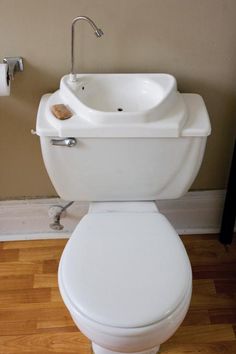 a white toilet sitting on top of a hard wood floor next to a bathroom sink