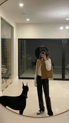 a man taking a photo of himself and his dog in front of a large mirror