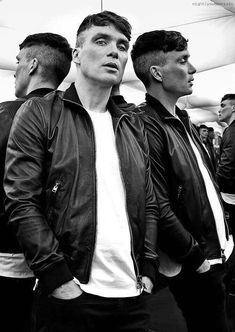 black and white photograph of three men in leather jackets, one looking at the camera