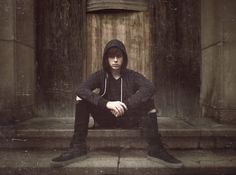 a young man sitting on the steps in front of an old building with his arms crossed