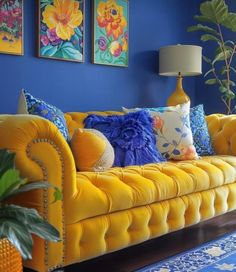 a living room with blue walls, yellow couches and colorful paintings on the wall