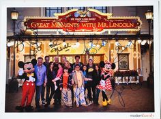 a group of people standing in front of a building with mickey mouse and other characters