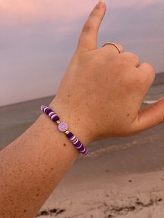 It is a purple and white clay bead bracelet with a plastic smiley face bead in the middle. It is an elastic string with a tie to complete it. Purple Clay Beads Bracelet, Black And Purple Clay Bead Bracelet, Purple Clay Bracelets, Casual Purple Friendship Bracelets With Letter Beads, Casual Purple Friendship Bracelet With Letter Beads, Purple Stretch Bracelet With Letter Beads, Purple Friendship Bracelets With Letter Beads, Adjustable Purple Beaded Bracelets With Letter Beads, Adjustable Purple Letter Beads Bracelet