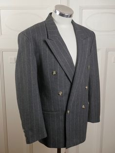 This handsome gray pinstripe double-breasted blazer has peak lapels and padded shoulders, and closes in the front with one faux tortoiseshell button (six in total show on the front). Three buttons also decorate each sleeve edge. The German jacket has three pockets on the front, and is lined in a silvery gray satin viscose fabric. Brand: International Style (Germany) Size: 40 US/UK Material: 70% wool, 30% polyester Condition: Excellent (clean, soft, and supple, with no stains, tears, wear spots, Indian Frocks, Best Blazer, Pinstripe Blazer, Mens Sport Coat, International Style, Wool Blend Jacket, Breasted Blazer, Double Breasted Blazer, Zipper Jacket