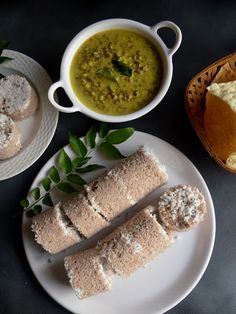 some food is sitting on a white plate next to bowls and breadsticks with dipping sauce in them