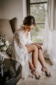 a woman sitting on top of a chair next to a glass vase filled with flowers