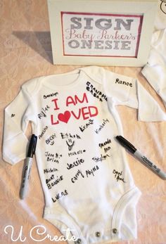 a baby's bodysuit with writing on it next to a sign that says i am loved