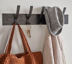 two purses hanging on the wall next to a coat rack and hat hanger