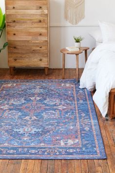 a large blue rug in a bedroom next to a wooden dresser and bed with white sheets