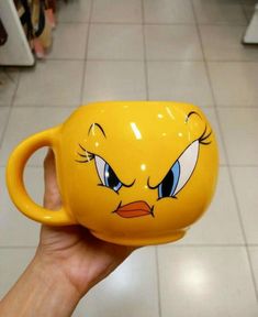 a person holding a yellow coffee mug with angry birds on it's face and eyes