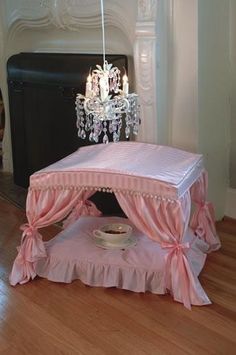 a pink baby crib with a chandelier hanging from it's ceiling