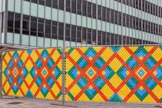 a colorful fence is in front of a tall building