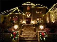 a house with christmas lights and wreaths on the front steps