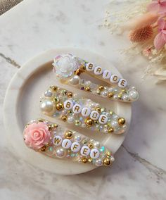 three hair clips with flowers on them sitting on a plate next to a flower bouquet