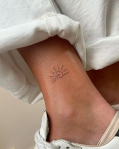 a woman's foot with a small sun tattoo on the side of her ankle