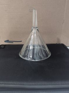 a glass cone sitting on top of a black suitcase