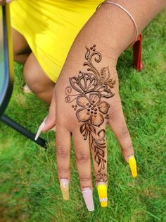 a woman's hand with henna tattoos on it and yellow nail polishes