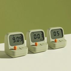 three alarm clocks sitting side by side on a table