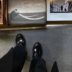 a person standing in front of a wall with pictures on it and their feet propped up