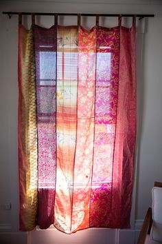 the curtains are hanging in front of the window and light coming through them is shining brightly