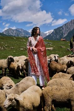 a woman standing in front of a herd of sheep