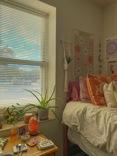 a bedroom with a bed, window and various items on the table in front of it