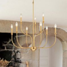 a gold chandelier hangs from the ceiling in front of a brick fireplace and stone mantel