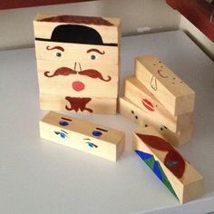 three wooden blocks with faces and mustaches on them sitting on a white counter top