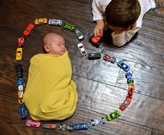 a baby wrapped in a blanket is surrounded by toy cars on the floor and around him