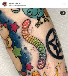 an arm with colorful tattoos on it and stars, moon, and other things in the background