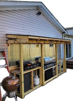 an outdoor bbq with grill and ladders next to it on the side of a house