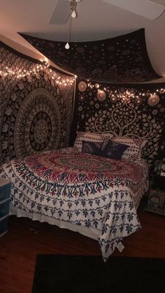 a bed in a room with lights strung from the ceiling and a tapestry on the wall