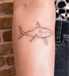 a small shark tattoo on the arm