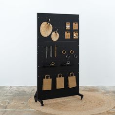 a black display case with several items hanging on it's sides and two bags attached to the wall