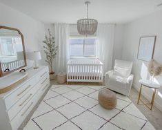 a living room with white furniture and a large mirror on the wall above the crib