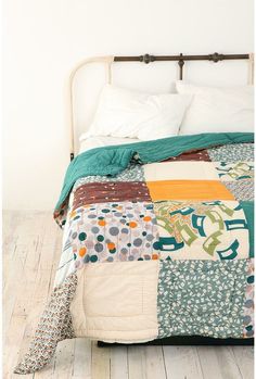 the bed is made up with colorful quilts