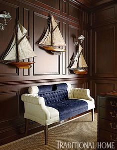 a living room with wooden paneling and two sailboats mounted on the wall above it