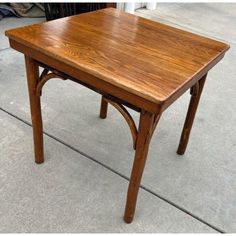 a wooden table sitting on top of a cement floor next to a sidewalk with no one around it