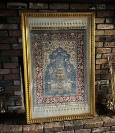 an old rug hanging on a brick wall next to a vase with flowers in it