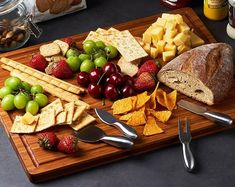 a wooden cutting board topped with fruit and crackers