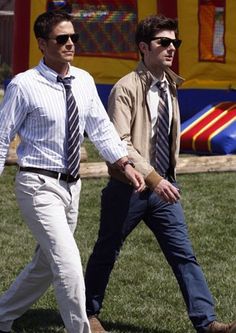 two men walking in the grass near a bouncy house with an inflatable bouncer