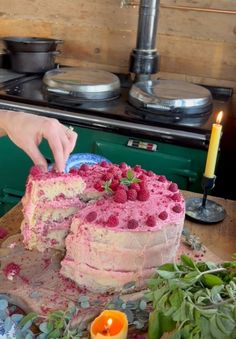 a person is cutting into a cake with raspberries on the top and bottom