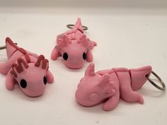 three pink dragon key chains on a white surface